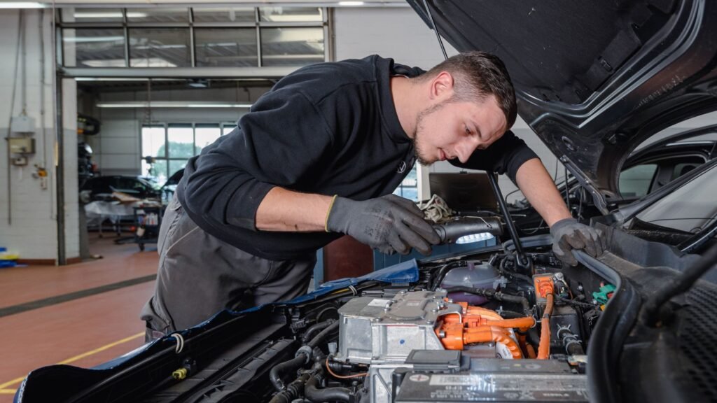 Ein Kfz-Mechatroniker blickt in den Motorraum eines Autos.