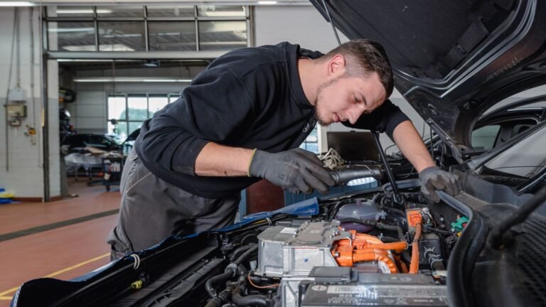 Ein Kfz-Mechatroniker blickt in den Motorraum eines Autos.